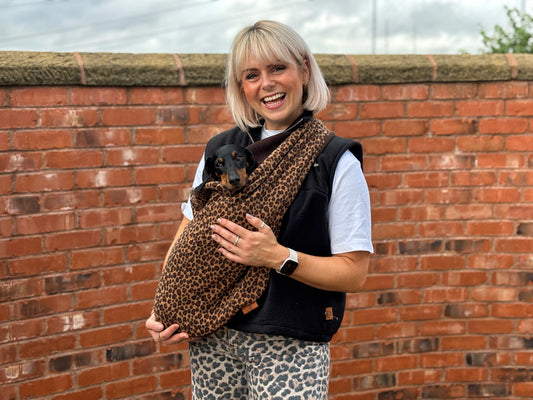 Woman by a brick wall wearing a leopard print fleece dog sling