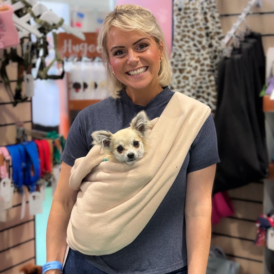 Woman holding a small dog in a sling in a store setting