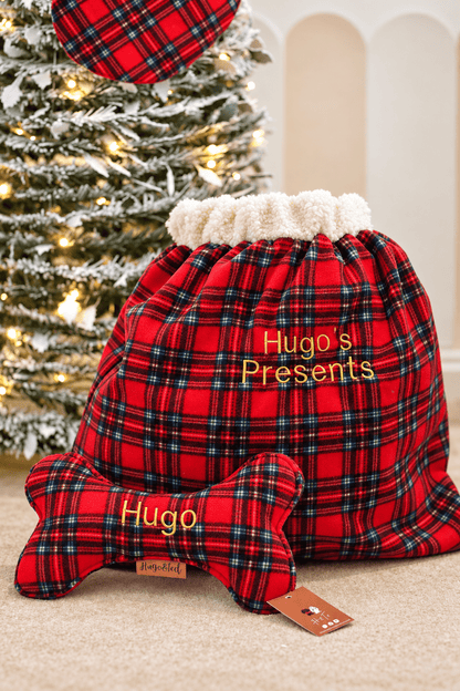 Red tartan wonky bone and present sack in front of a Christmas tree