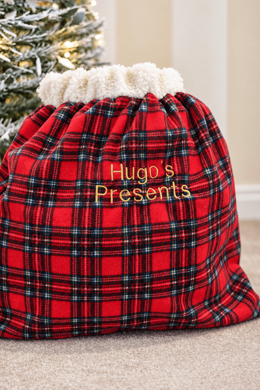 Red tartan present sack embroidered Hugo's Presents, front view
