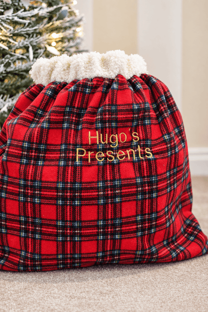 Red tartan present sack embroidered Hugo's Presents, front view